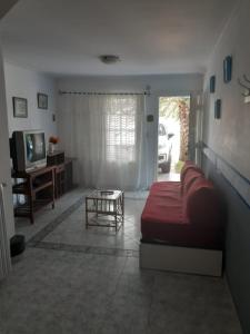 a living room with a red bed and a tv at Lejos de Pindal in Santa Clara del Mar