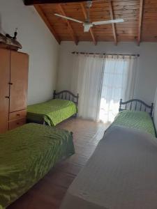 2 camas en una habitación con sábanas verdes y una ventana en Lejos de Pindal en Santa Clara del Mar