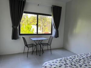 een slaapkamer met een tafel en stoelen en een raam bij METRO HOMESTAY in Bao Loc