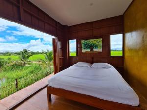 a bedroom with a bed with a view of a field at Ha Me Garden ฮามีการ์เด้น โฮมสเตย์ฝาง in Fang