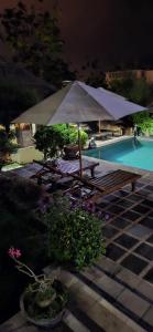 uma mesa de piquenique e um guarda-sol ao lado de uma piscina em Villa Anjing em Nusa Dua