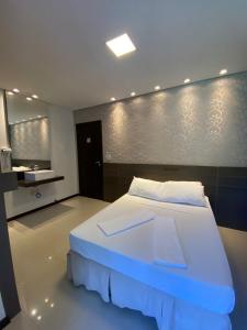 a bedroom with a large white bed and a sink at Spazio Vital Apartments in Florianópolis
