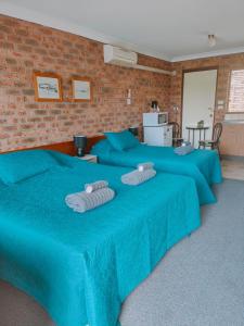 duas grandes camas azuis com toalhas por cima em Hills of Gold Motel at Nundle em Nundle