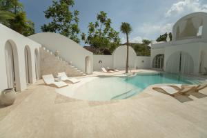 a swimming pool with lounge chairs and a house at MAJA Canggu in Canggu