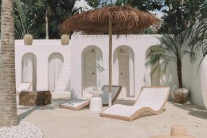 a patio with chairs and an umbrella and palm trees at MAJA Canggu in Canggu