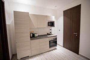 a kitchen with white cabinets and a wooden door at Veronique Heights in Kumasi