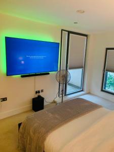 a bedroom with a large flat screen tv on the wall at JJ Luxury Apartment in London