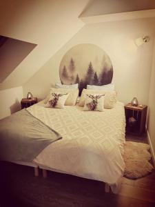 una camera da letto con un letto bianco con un dipinto sul muro di La Parenthèse a Betton