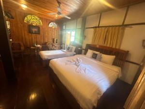 a bedroom with two beds with white sheets at XiengThong KhounPhet GuestHouse in Luang Prabang