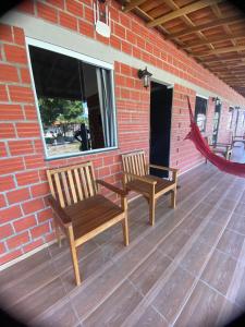 duas cadeiras de madeira sentadas num deque ao lado de uma parede de tijolos em POUSADA ALLES em Santo Amaro