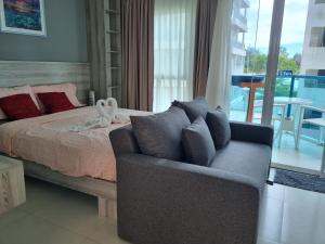 a bedroom with a bed and a couch and a balcony at Grandblue condominium 106,302 in Mae Pim
