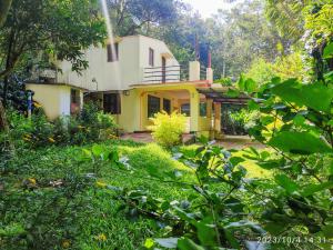 a yellow house in the middle of a garden at Comfort Cottage in Yercaud