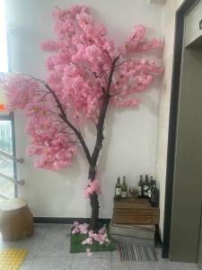 einen Baum mit rosa Blumen an der Wand in der Unterkunft Hanra guesthouse in Jeju-do