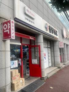 ein Geschäft mit einer roten Tür in einem Gebäude in der Unterkunft Hanra guesthouse in Jeju-do