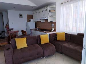 sala de estar con sofá marrón con almohadas amarillas en Hermoso Departamento en Atacames, en Atacames