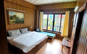 um quarto com uma cama e uma grande janela em Mussoorie Homestay em Mussoorie