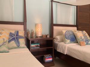 a bedroom with two beds and a nightstand between them at Ban Laem Set - Beachfront Private Luxury Villa in Laem Set Beach