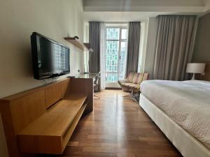 a hotel room with a bed and a flat screen tv at Cormar KLCC by NHB in Kuala Lumpur