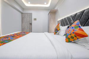 a bedroom with a large white bed with colorful pillows at FabHotel Aahan in Navi Mumbai