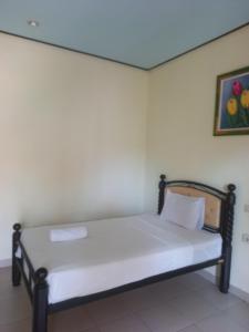 a bed in a room with a picture on the wall at ANUGRAH GILI AIR in Gili Islands