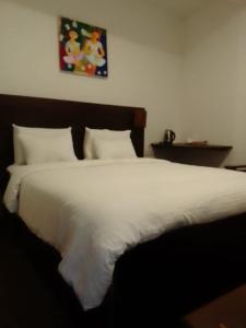 a large bed with white sheets and pillows at MANUDI Glenfallsedge Rest in Nuwara Eliya