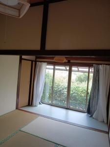 a room with a large window with white curtains at ゲストハウス ふしの庵 in Ogori
