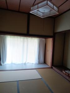 Habitación con ventana y cortina blanca en ゲストハウス ふしの庵 en Ogori
