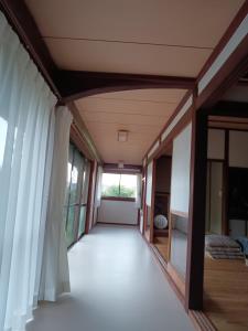 un pasillo de una casa con cortinas y una ventana en ゲストハウス ふしの庵 en Ogori