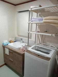 y baño con lavadora y lavamanos. en ゲストハウス ふしの庵 en Ogori