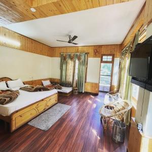 a bedroom with a bed and a flat screen tv at The White House in Kasol