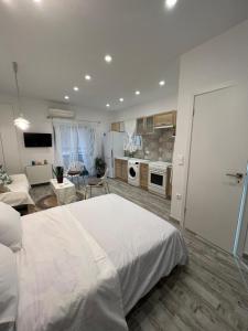 a bedroom with a white bed and a living room at Selenity studio(close to two metro stations) in Piraeus