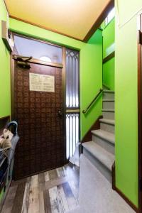 a door in a room with green walls and stairs at Sprinkle inn in Sapporo