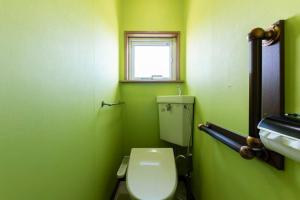 a green bathroom with a toilet and a window at Sprinkle inn in Sapporo