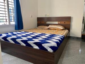 a bed with a blue and white comforter on it at Luxury Queen Bed Suite 6km to Palace with Farm Land and Hill View in Mysore