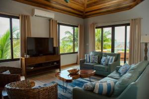 een woonkamer met een bank en een tv bij Island Time Gecko in Placencia Village