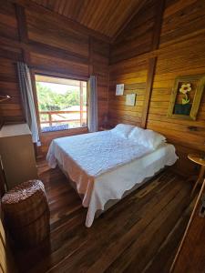 a bedroom with a bed in a wooden room at Chalé do Beco - Nova Caraíva in Porto Seguro