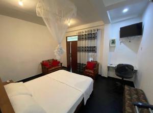 - une chambre avec un lit, deux chaises et une télévision dans l'établissement Pink Lotus Villa, à Unawatuna