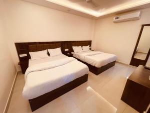 Habitación de hotel con 2 camas con sábanas blancas en White House - A Four Star Luxury Resort, en Haridwar