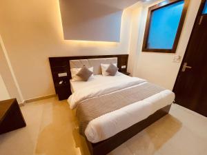 um quarto com uma cama grande com lençóis brancos e uma janela em White House - A Four Star Luxury Resort em Haridwar