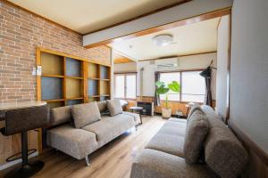 a living room with two couches and a brick wall at YADOt Inn OTARU in Otaru