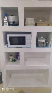 a white cabinet with a microwave in a kitchen at Квартира-студия с видом на море in Ureki