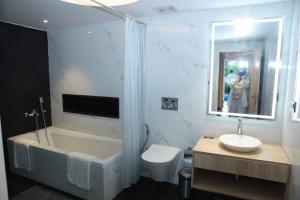 ein Badezimmer mit einer Badewanne, einem WC und einem Waschbecken in der Unterkunft Gracias Cafe & Resort in Morjim