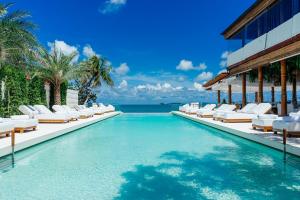 a swimming pool with lounge chairs and the ocean at Zazen Boutique Resort & Spa in Bophut