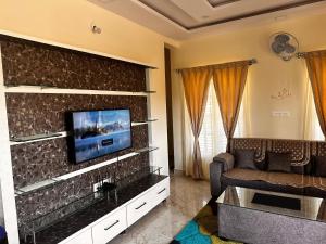 - un salon avec un canapé et une télévision murale dans l'établissement DEEYA Guest House, à Mysore