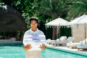 a man holding a pile of towels by a swimming pool at Zazen Boutique Resort & Spa in Bophut