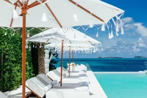 a row of white chairs and umbrellas next to a pool at Zazen Boutique Resort & Spa in Bophut