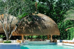 a swimming pool with a straw umbrella and chairs at Zazen Boutique Resort & Spa in Bophut
