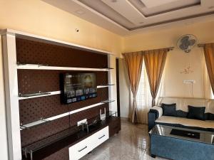 een woonkamer met een bank en een tv aan de muur bij DEEYA Guest House in Mysore