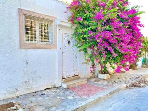 uma casa branca com flores cor-de-rosa e uma porta em S+1 au cœur de la Marsa plage em La Marsa