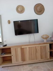 a flat screen tv sitting on top of a wooden entertainment center at - Les pieds dans l'eau à 50m de la plage, côté mer caraïbe - Domaine de l'Anse CARITAN - Sainte-Anne - in Sainte-Anne